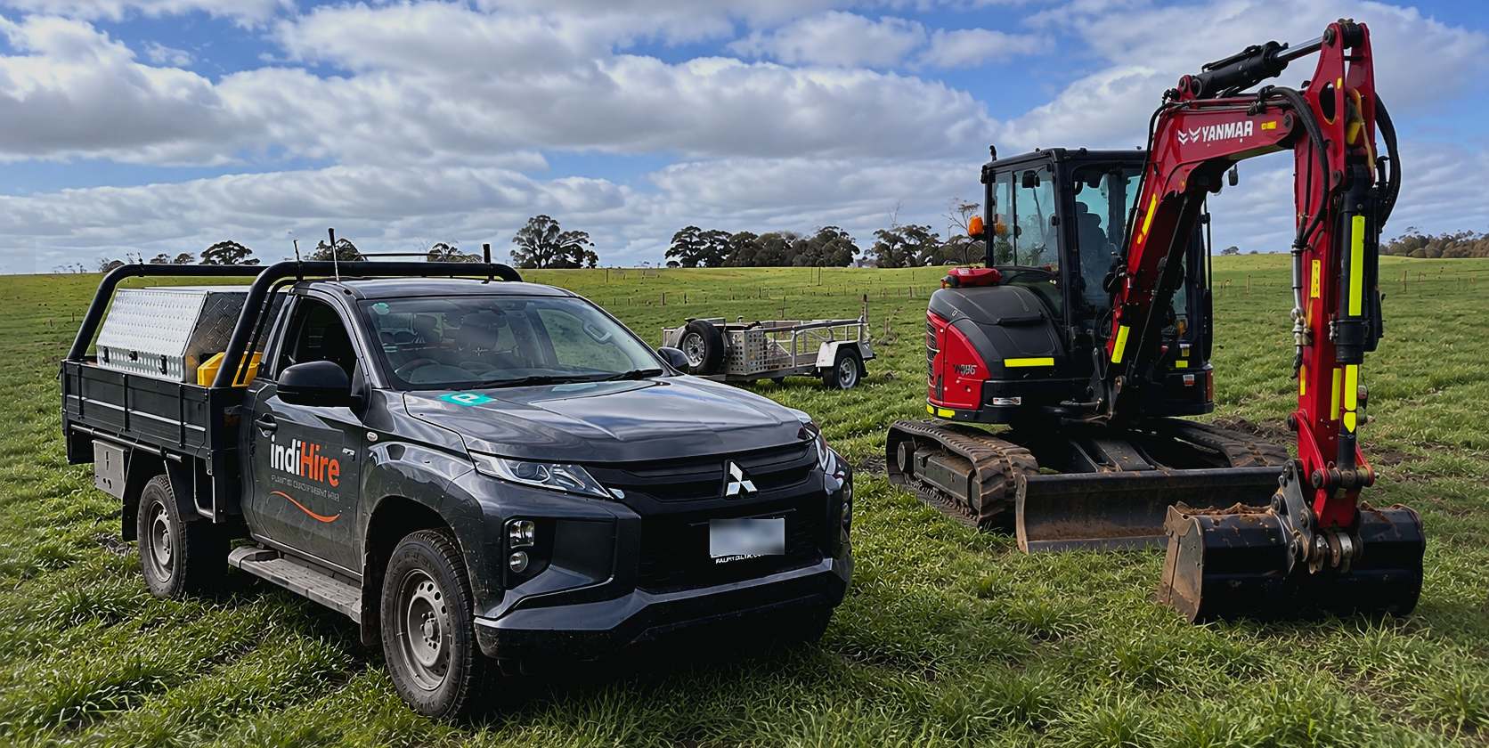 An Indi Hire ute and a Yanmar excavator with a spoil trailer, parked in an open paddock.